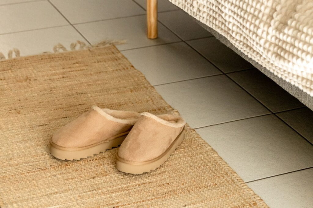 UGG Tasman Slippers next to a daytime bed