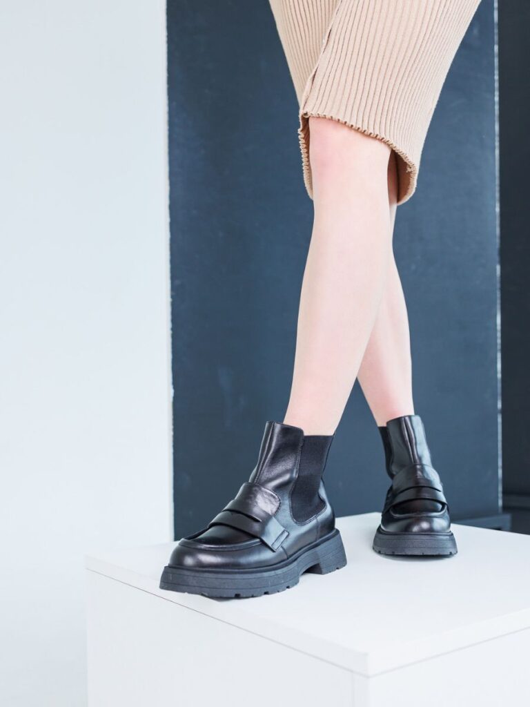 Close-up of lady in beige skirt and black leather chelsea boots