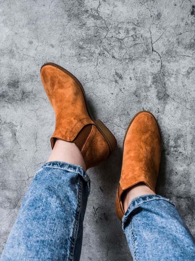 A Stylish woman wearing cropped jeans with chelsea suede boots