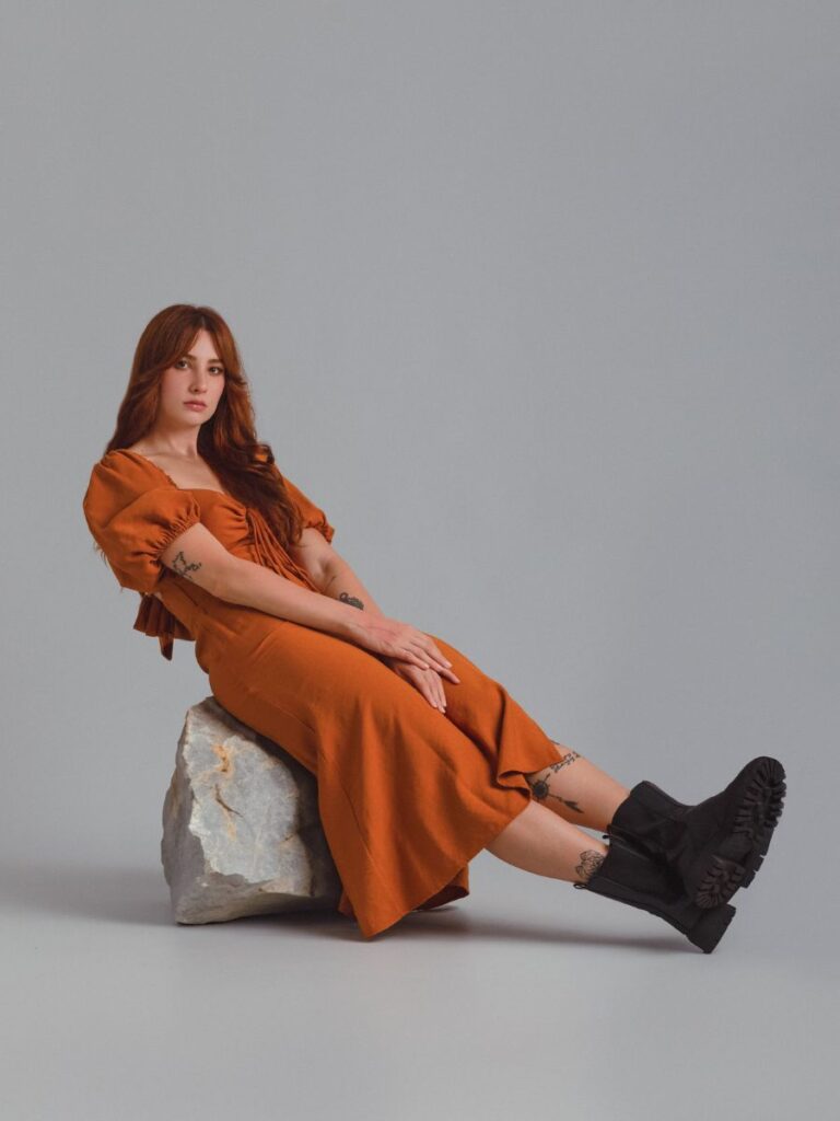 Model in an Orange Midi Dress and Chelsea Boots Sitting on a Rock