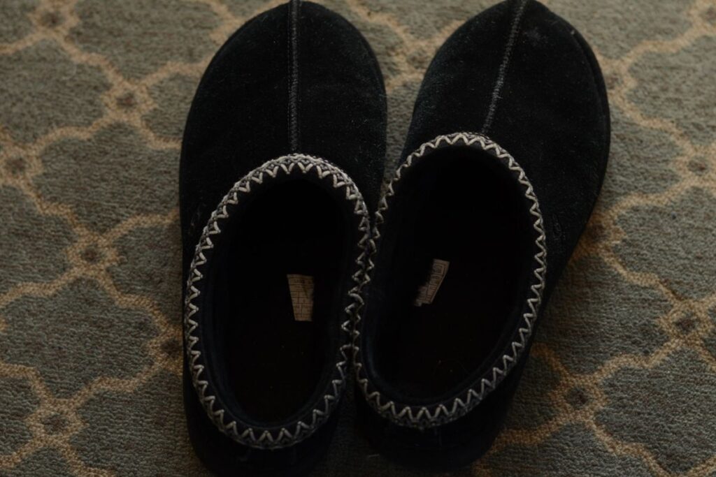 UGG Tasman Slippers in black, featuring the signature embroidered UGG braid collar